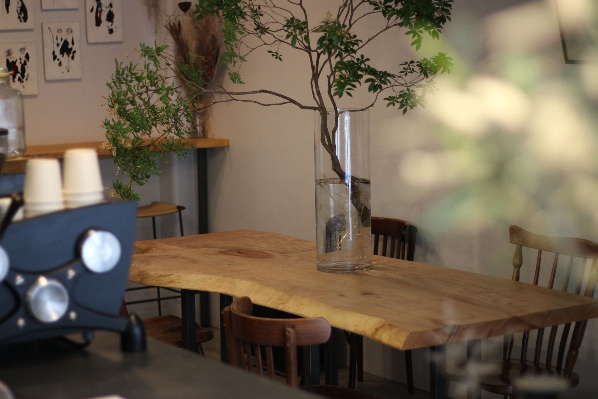 PAUSE COFFEEの木のテーブルと枝を生けた花瓶